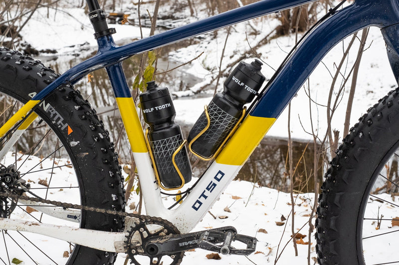 Load image into Gallery viewer, Wolf Tooth Morse Cage Ti Limited Edition - 64mm Mounts, 33g Ultra-Light Gold Titanium Bicycle Bottle Cage with 4-Position Adjustment, Handcrafted American Engineering, Low Profile, Durable, and Flexible for Cycling Enthusiasts